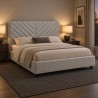 Cama tapizada Chevron en un dormitorio de noche iluminado por lámparas de mesilla