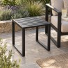 Stalowy stolik boczny do ogrodu, obok fotela ogrodowego na kamiennym tarasie