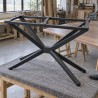 Base per tavolo a ragno in acciaio, capovolta in officina mentre si fissa un piano in legno