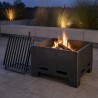 Palenisko stalowe z rusztem grillowym, ruszt zdjęty, na kamiennym tarasie o zmierzchu
