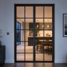 Porta Loft in Acciaio a Due Ante, chiusa, con cucina illuminata sullo sfondo di sera