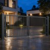 Zweiflügeliges Einfahrtstor aus Stahl, in der Dämmerung vor beleuchtetem Haus