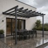 Pérgola de acero con vigas vistas, sobre una terraza con comedor bajo la lluvia